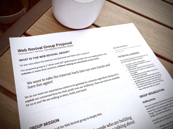Printed documented titled "Web Revival Group Proposal" lying on a table. The headline reads "What is the Web Revival Group"